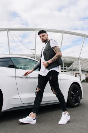 Kamizelka skórzana męska w kolorze czarnym, z modnymi przetarciami, noszona na białej koszulce