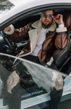 Męski kożuch w brązowym kolorze, z białym futrem, zapinany na zamek, z klasycznym kołnierzem i kieszeniami