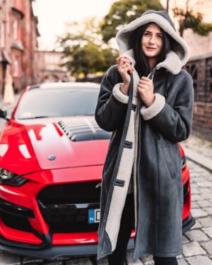 Kożuch damski w kolorze szarym z kapturem, wykończony jasnym futrem, z guzikami i długim krojem