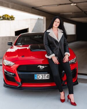 Kożuch damski z futrzanym kołnierzem, w kolorze czarnym, z metalowymi detalami i asymetrycznym zapięciem