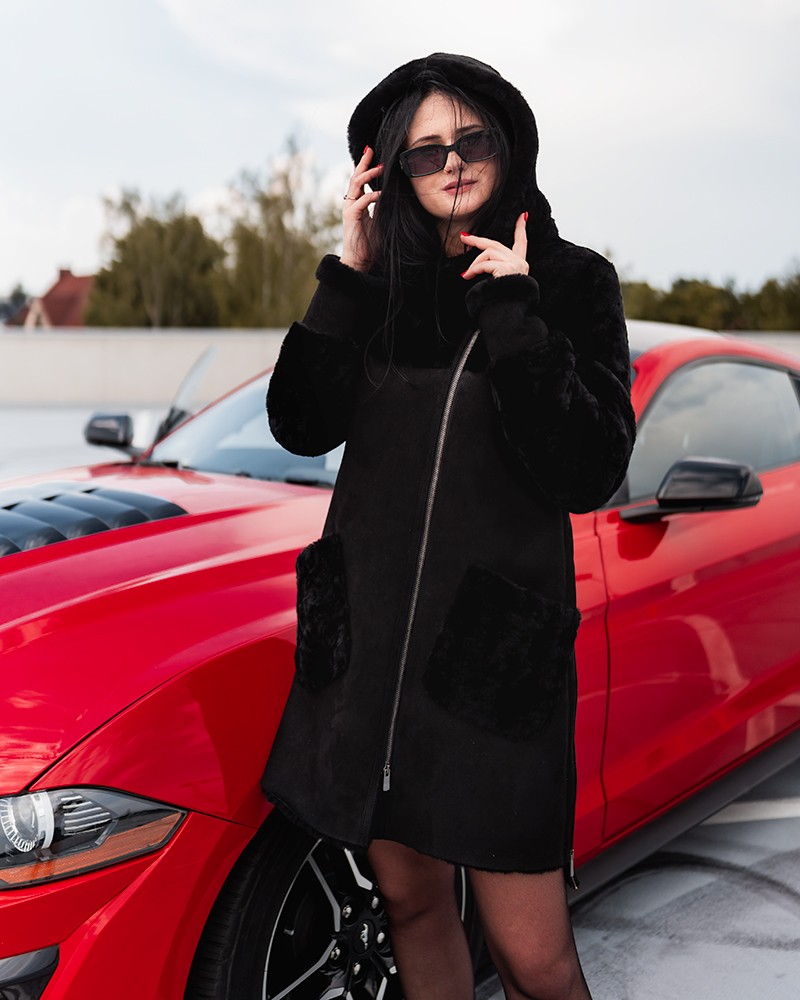 Kożuch damski w czarnym kolorze z kapturem, zamkiem i kieszeniami z futra, idealny na zimowe dni