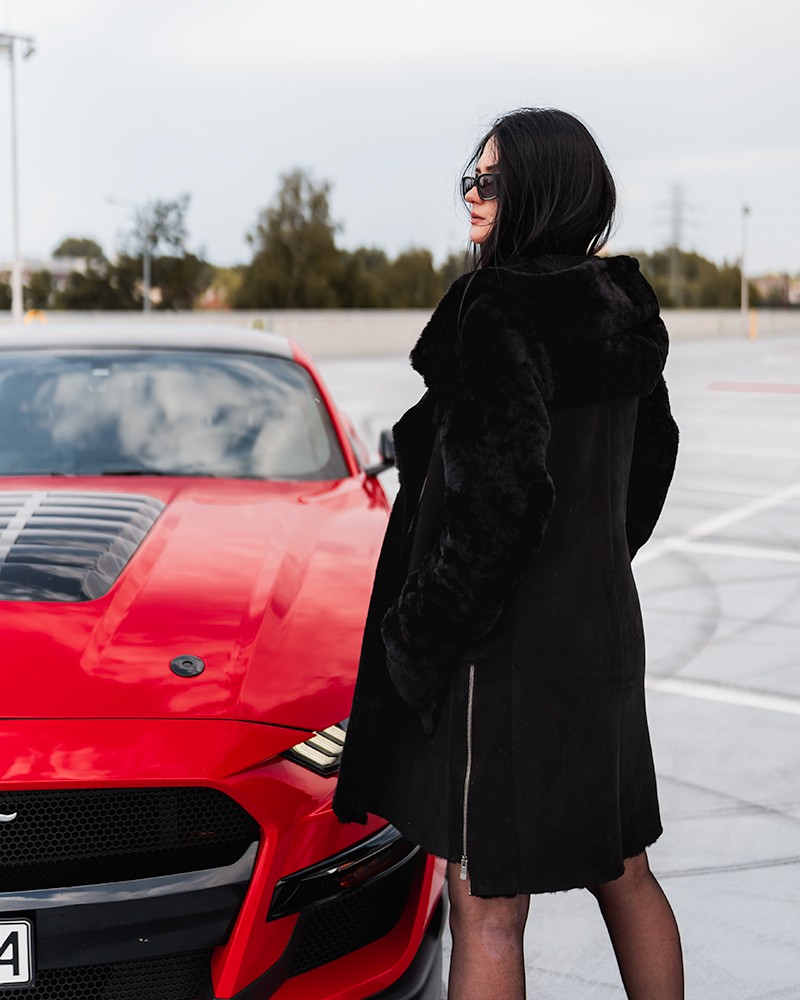 Czarny kożuch damski z kapturem i futrzanym wykończeniem, idealny na zimowe dni