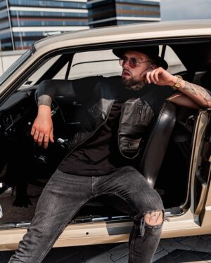 Kamizelka skórzana męska w czarnym kolorze z kieszeniami, noszona na czarnym t-shircie oraz z przetarciami na jeansach