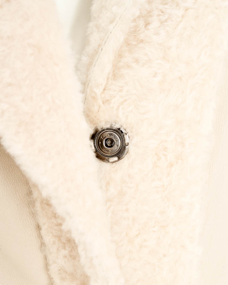 Kożuch damski w jasnym kolorze z miękkim futrzanym wykończeniem i metalowym guzikiem przy kołnierzu