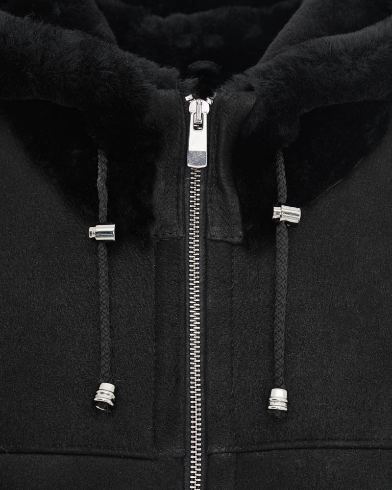 Czarny kożuch damski z kapturem i zamkiem, ozdobiony metalowymi detalami, idealny na zimowe dni