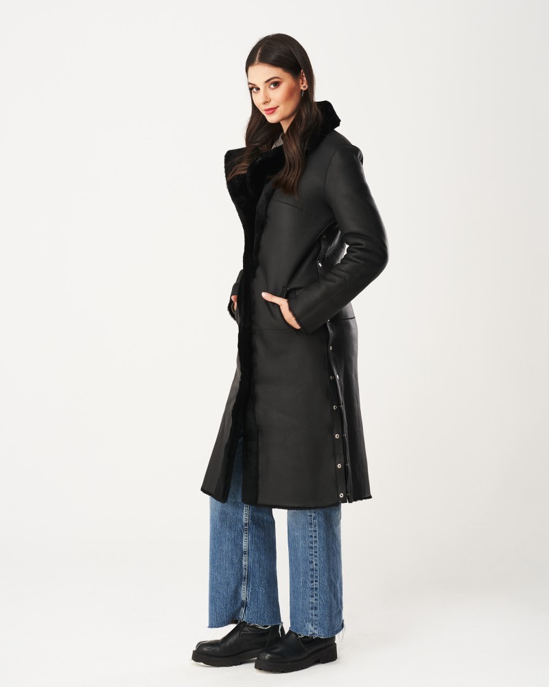 Czarny kożuch damski z długim krojem, z miękkim futrem przy kołnierzu i guzikami po bokach