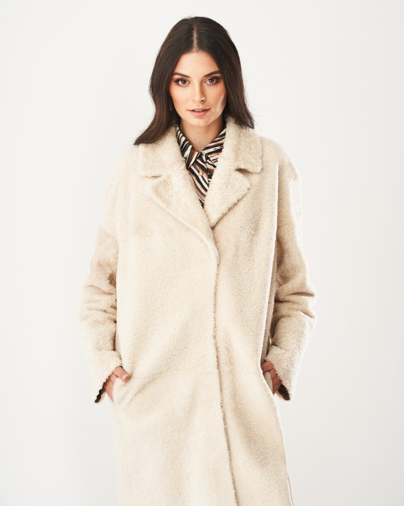 Kożuch damski w jasnym kolorze, o luźnym kroju, z dużymi kieszeniami i klasycznym kołnierzem